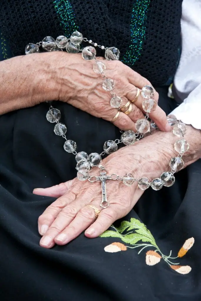 mature hands holding a crystal rosary