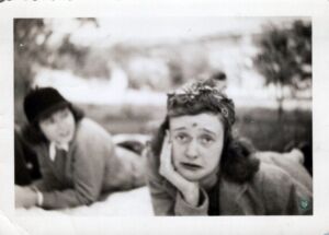 Black and white photo of a woman lying on a picnic blanket with a scraped forehead and nose making a sad face